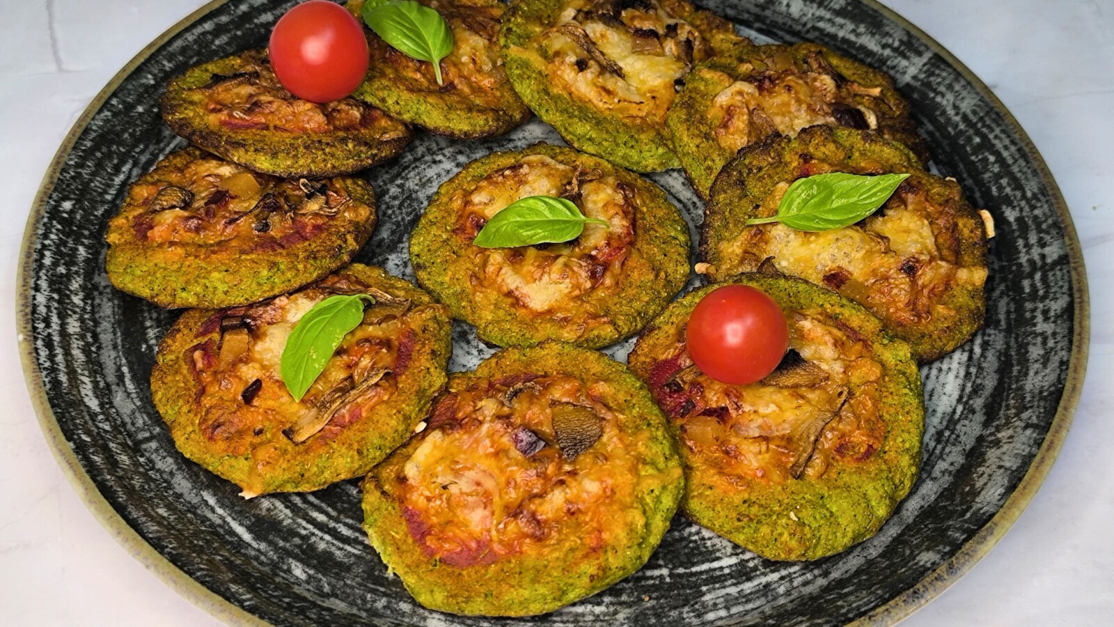 pizza-od-brokule Zlatno pečene pizzete od brokule ukrašene bosiljkom i cherry rajčicama.