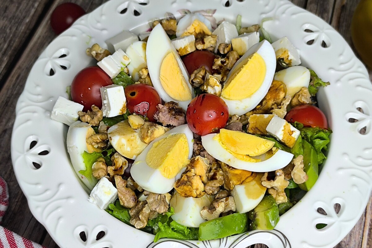 Gotova salata s jajima, tunom i avokadom bogato garnirana orasima i svježom rajčicom.