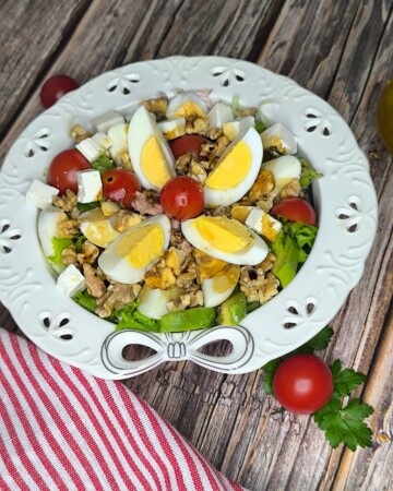 Zasitna salata s kuhanim jajima, tunom, avokadom i svježom zelenom salatom na rustikalnoj podlozi.