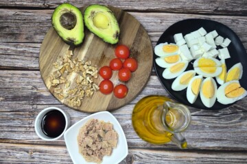 Sastojci za salatu s jajima, tunom i avokadom posloženi na drvenoj podlozi prije pripreme.