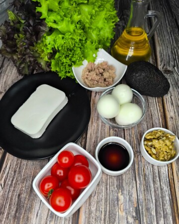 Priprema salate s jajima, tunom i avokadom s maslinovim uljem, feta sirom i svježim povrćem.