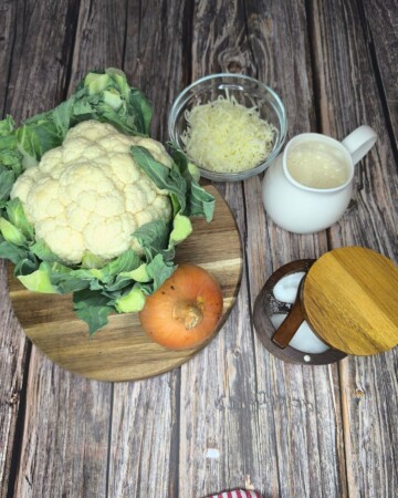 Svježa glavica cvjetače s naribanim sirom, jajima i začinima pripremljena za recept.