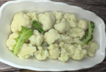 Kuhani cvjetovi cvjetače složeni u bijeloj posudi prije pripreme za pečenje.