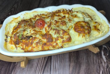 Pečena cvjetača u umaku sa sirom, gratinirana u ovalnoj posudi za pečenje.