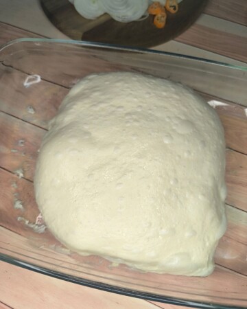 focaccia-priprema-tijesta Dignuto tijesto za focacciu na drvenoj podlozi spremno za oblikovanje