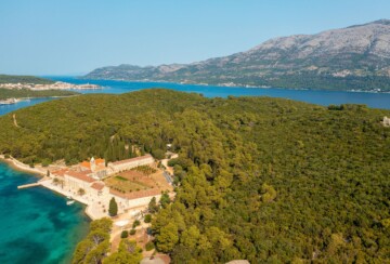Samostan smješten tik uz more na otočiću Badija, okružen gustom šumom i snimljen iz zraka