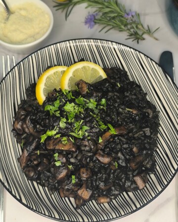 Crni rižoto od sipe serviran s kriškama limuna i svježim peršinom