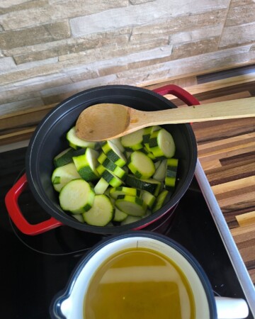 Dodavanje narezanih tikvica u lonac za juhu