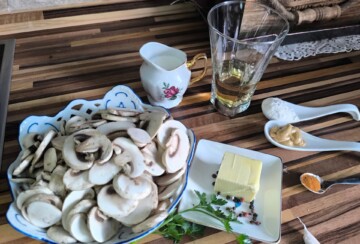 Svježi šampinjoni i ostali sastojci za pripremu jednostavnog domaćeg umaka od gljiva s vrhnjem i bijelim vinom.